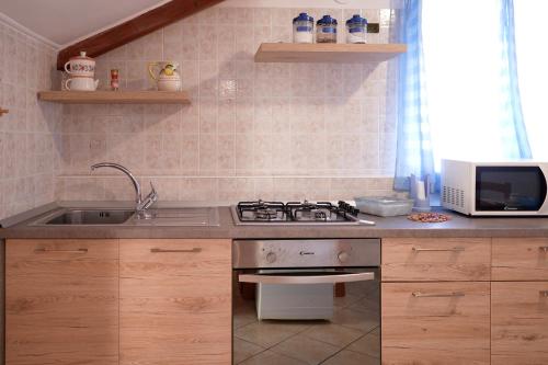 a kitchen with a sink and a stove and a microwave at Casa Vacanza Gialu in Erchie