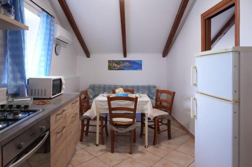 a kitchen with a table with chairs and a white refrigerator at Casa Vacanza Gialu in Erchie