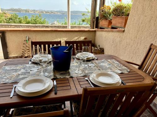 a wooden table with plates and wine glasses on it at Vista mare La Maddalena con posto Barca e posto Auto coperto in La Maddalena