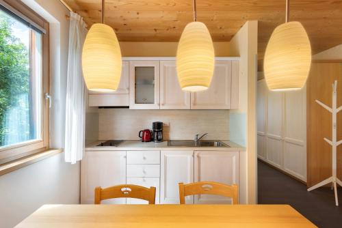 a kitchen with white cabinets and two lights at Silbernagl - Monolokal mit Ausblick in Issengo