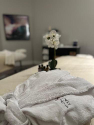 a white blanket on a bed with a vase with a flower at Cannery Pier Hotel & Spa in Astoria, Oregon