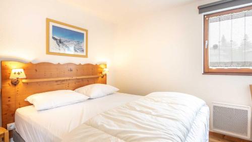 une chambre avec un lit avec des draps blancs et une fenêtre dans l'établissement V DU BACHAT - Asters D22 - Appt 5 pers, à Chamrousse