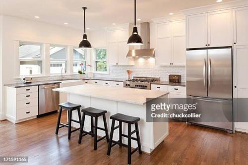 a kitchen with white cabinets and a large island with bar stools at New perfect home. in Koprivshtitsa