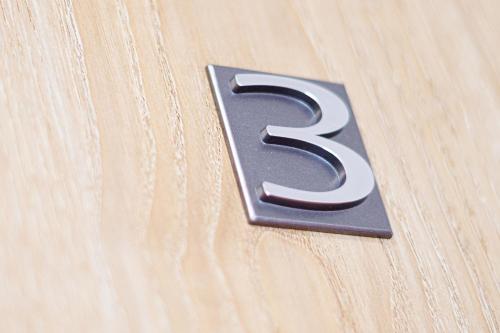 a metal number three on a wooden table at APARTMÁNY Sninský dvor in Snina