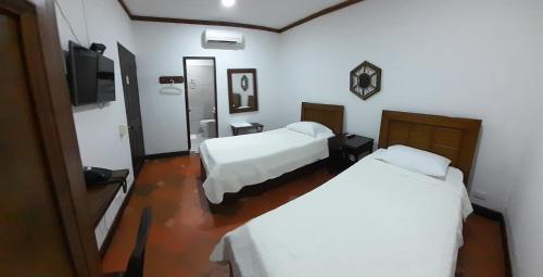 a hotel room with two beds and a television at Hotel Frutas del Lago in Caucasia