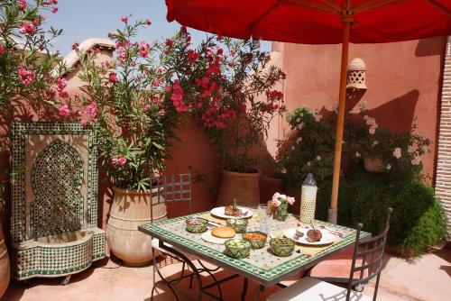 una mesa con platos de comida y una sombrilla roja en Riad Chameau FDC Hôtel SPA, en Marrakech