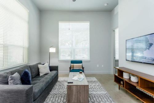 a living room with a couch and a flat screen tv at Peony At Millennium - Elegant 2 Bed Apt in Houston in Houston