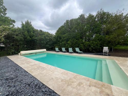 une piscine avec des chaises dans une cour dans l'établissement Les Quatre Saisons de Chambord, à Maslives