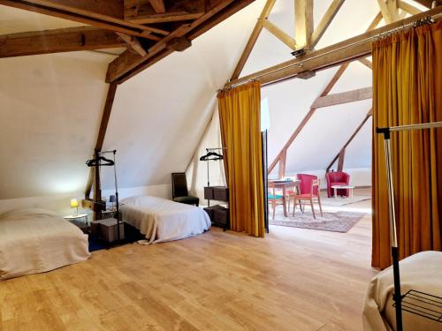 an attic bedroom with two beds and a dining room at Les Tamaris 4 étoiles in Omonville-la-Rogue