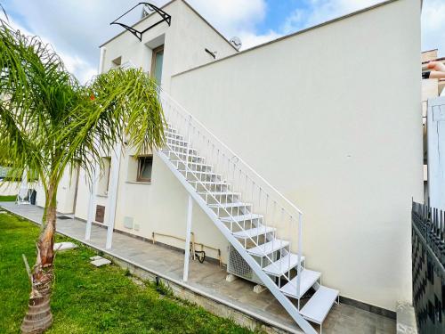 a white staircase on the side of a building with a palm tree at Suite Capaci in Capaci