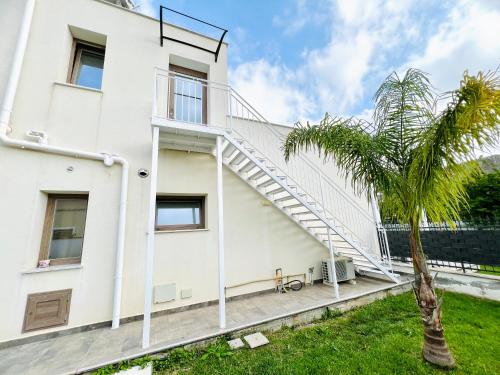 a white house with a staircase on it with a palm tree at Suite Capaci in Capaci