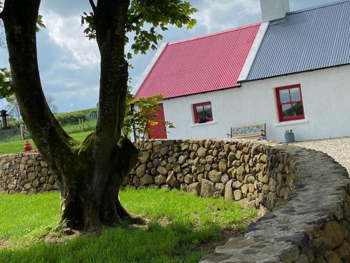 a tree in front of a stone wall next to a building at Farm Stay at THE GLEBE COTTAGE KILREA in Tamlaght