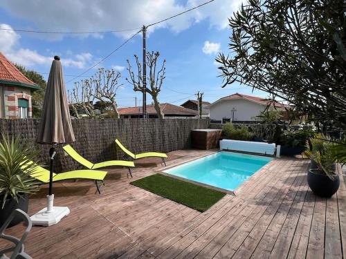 une cour avec une piscine, des chaises et un parasol dans l'établissement VILLA NIKITA Plage, à Andernos-les-Bains