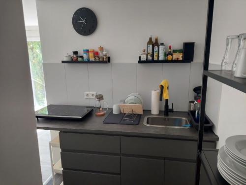 een aanrecht met een wastafel en een klok aan de muur bij City-Apartment in Dortmund