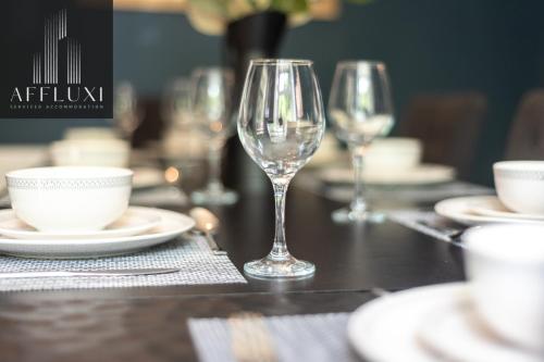 a table with two wine glasses and plates on it at Ironbridge Hot Tub Retreat - Sleeps 10 in Telford