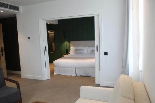 a bedroom with a white bed and a couch at Mondragon Hotela in Arrasate - Mondragon