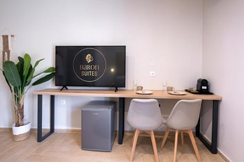 a desk with a television on it with two chairs at Baron Suites in Vasiliki