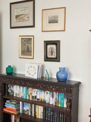 a book shelf filled with books and pictures on a wall at Logierhaus Extra in Norderney