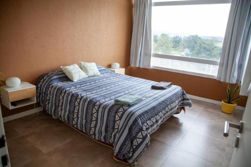 a bedroom with a bed with a blue blanket and a window at Hermoso Triplex en Sierra de la Ventana in Sierra de la Ventana