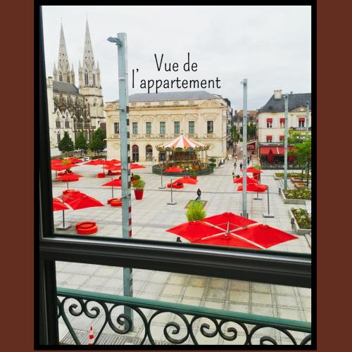 une vue depuis une fenêtre d'une cour avec des parapluies rouges dans l'établissement L'Éclat Travot Central Lumineux Vue Sublime, à Cholet