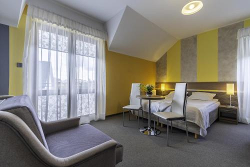 a hotel room with a bed and a table and chairs at FRAJDA Dom Wypoczynkowy in Rewal