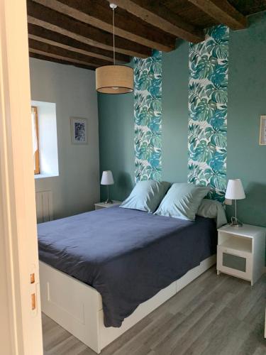 a bedroom with a large bed with blue walls at Gîte au cœur des vignobles in Lazenay