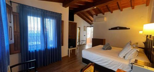 a bedroom with a bed and a large window at Hospedium Hotel Rural Abadía de Yuste in Cuacos de Yuste