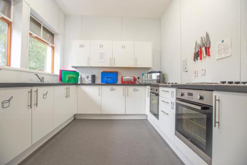 a white kitchen with white cabinets and appliances at Crianlarich Youth Hostel in Crianlarich