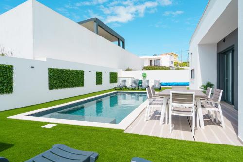 Un patio con mesa y sillas junto a una piscina. en Villa Venus with jacuzzi and private pool, en Lourinhã