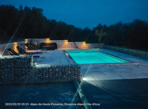 - une piscine avec un mur en pierre à côté d'une terrasse dans l'établissement Villa climatisée avec Piscine privée, à Volonne