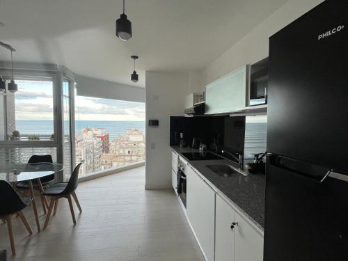 a kitchen with a table and a view of the ocean at Excelente! Vista al mar con cochera y amenities gimnasio, play room y pileta no climatizada in Mar del Plata