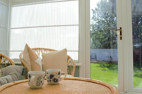 two cups sitting on a table in front of a window at Family Seaside Bungalow - Max 6 Adults Only in Margate