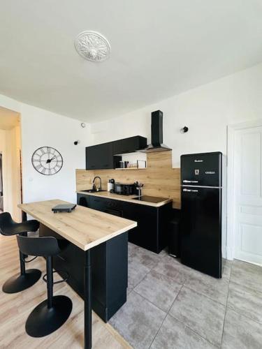 Il comprend une cuisine équipée d'un réfrigérateur noir et d'une table. dans l'établissement Charmant Appartement T4, à Le Teil