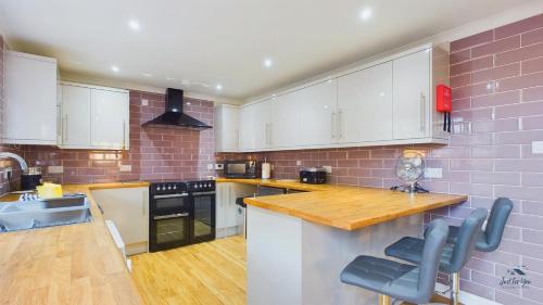 a kitchen with white cabinets and a brick wall at Dartmouth House in Totland