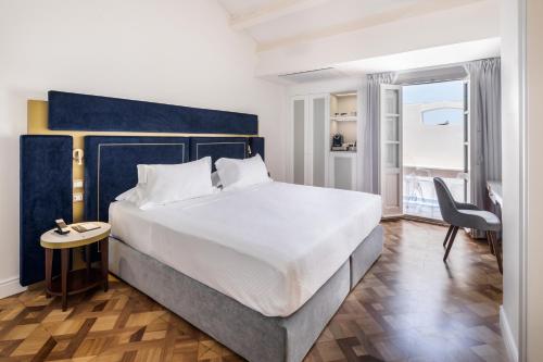 a bedroom with a large bed and a chair at Palazzo Artemide - VRetreats in Siracusa