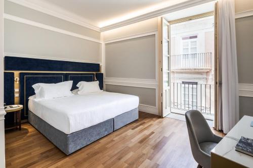 a bedroom with a bed and a desk and a window at Palazzo Artemide - VRetreats in Siracusa