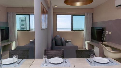a dining room with a table and a living room at Beach Class Excelsior - Flat 1 quarto no Pina por Yolo in Recife