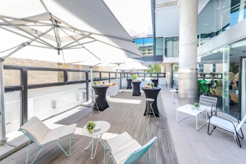 a balcony with chairs and tables on a building at Eurostars Málaga in Málaga
