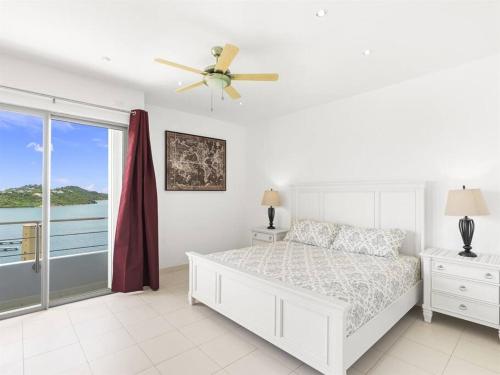 a white bedroom with a bed and a window at Breathtaking Lagoon Views At Blue Residence in Cupecoy
