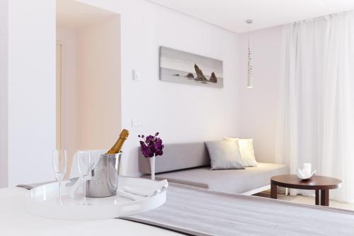 a white living room with a couch and a table at Hotel Garbi Ibiza & Spa in Playa d'en Bossa