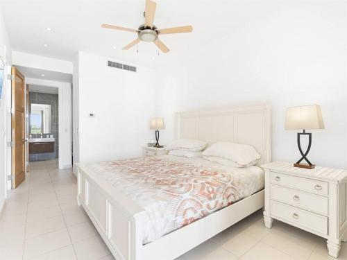 a white bedroom with a bed and a ceiling fan at Breathtaking Lagoon Views At Blue Residence in Cupecoy