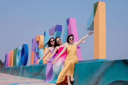 three women are posing in front of a wall at Flamingos Hải Tiến in Nam Khê