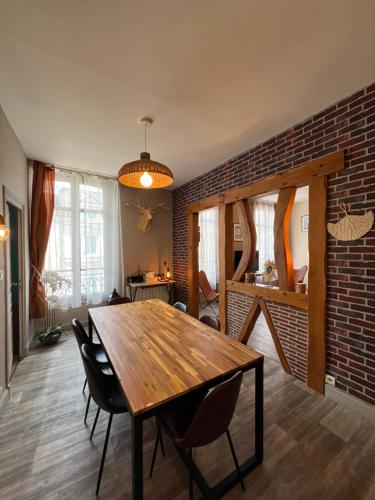 une salle à manger avec une table en bois et un mur en briques dans l'établissement Côté Château - Grand appartement au cœur de Blois, à Blois