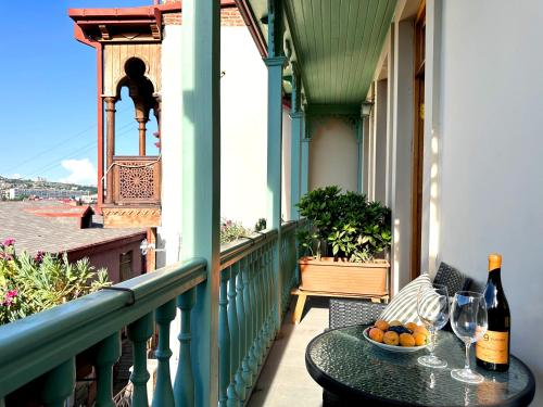 a table with a bottle of wine and a bowl of fruit on a balcony at Betlemi Old Town Hotel in Tbilisi City