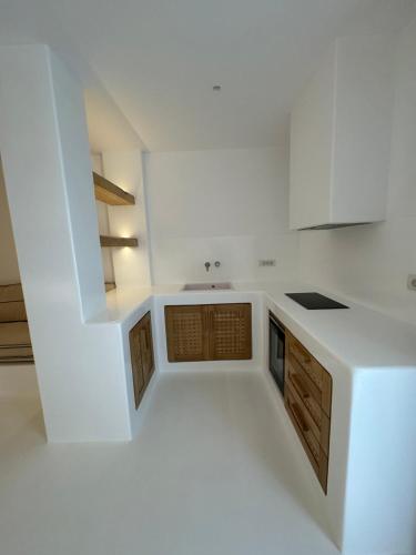 a kitchen with white cabinets and a sink at Yialos Ios Hotel in Ios Chora