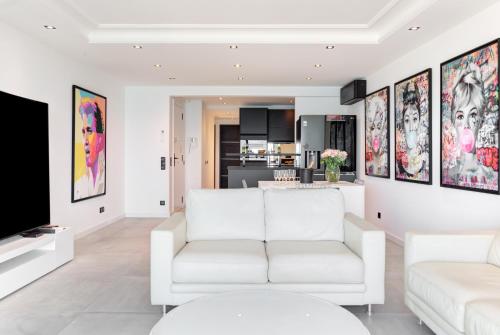 - un salon avec des meubles blancs et des peintures sur les murs dans l'établissement Croisette sea view, à Cannes