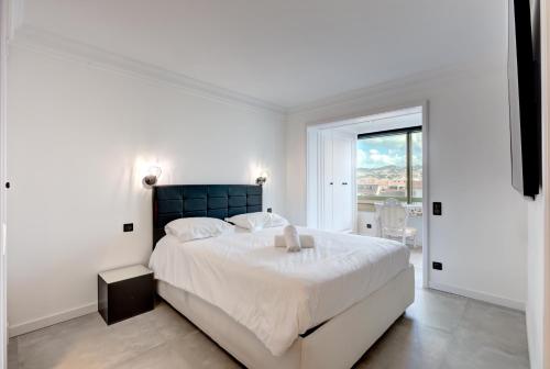 une chambre blanche avec un grand lit et une fenêtre dans l'établissement Croisette sea view, à Cannes
