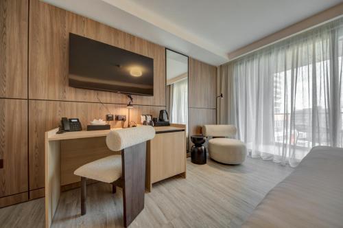a hotel room with a bed and a desk with a television at Noru Hotel Malta - Adults Only Hotel in St Julian's