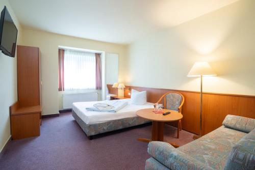 a hotel room with a bed and a table and a couch at Waldhotel Schöneiche -Self Check-In- in Schöneiche