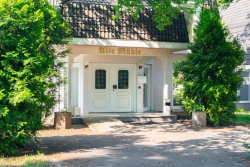a white house with a white door with a smile sign on it at Waldhotel Schöneiche -Self Check-In- in Schöneiche